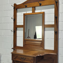 Impressive Oak hall stand of grand portions. Plenty of storage with a drawer, plenty of hooks and two sections for umbrealls/ walking sticks. It is in good original detailed condition.
