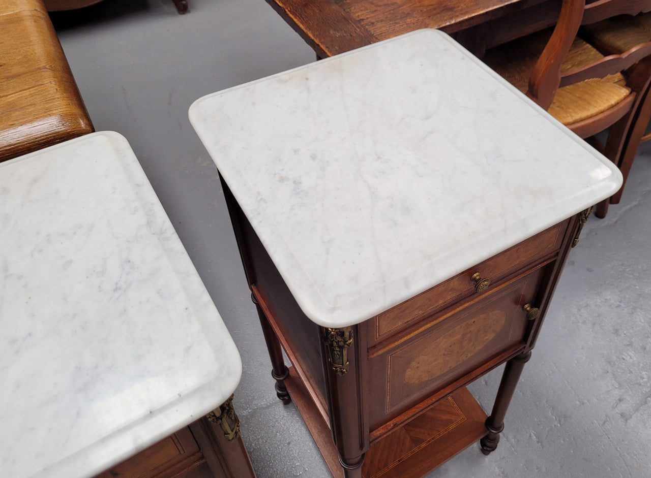 Pair of white marble topped Louis 16th style bedside cabinets consisting of one drawer and one cupboard.  Inlaid with burr walnut and has decorative mounts. They have been sourced from France and are in good original condition.