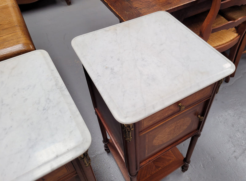 Pair of white marble topped Louis 16th style bedside cabinets consisting of one drawer and one cupboard.  Inlaid with burr walnut and has decorative mounts. They have been sourced from France and are in good original condition.
