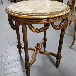 French Louis XVI style round marble topped gilded lamp/side table featuring lovely carved swags and undercarriage. It has been sourced from France and is in good original detailed condition.