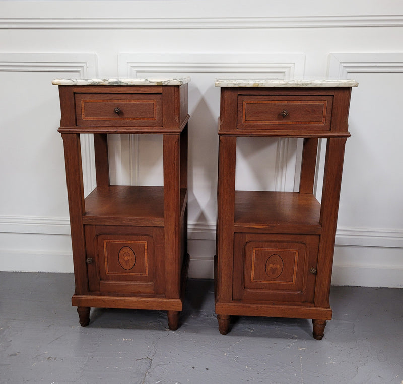 Pair of Antique French Oak Louis XVI style marble top bedside cabinets. They have decorative inlay and have been sourced from France. They are in good original detailed condition.