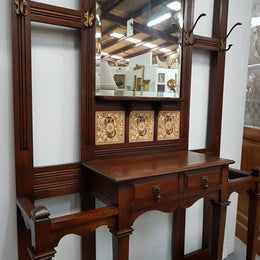 Beautiful English Edwardian tiled back hall stand, with nine brass hooks, two small drawers and retaining it's original mirror and showing signs of age. In good original condition.