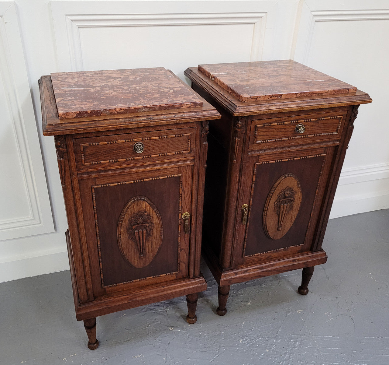 Pair of French Art Deco Oak and rouge inset marble top bedside cabinets. They have one drawer and one cupboard with elegant carving on the door. They have been sourced from France and are in good original detailed condition.