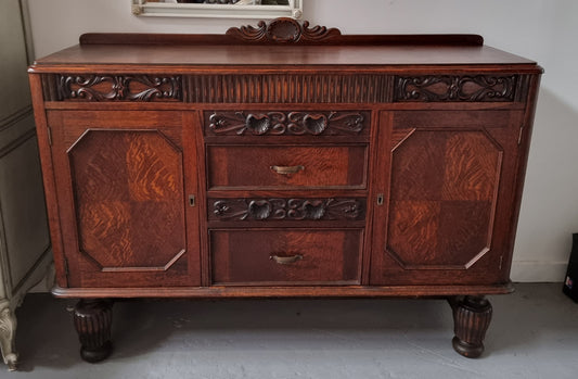 Art Deco Tudor style Oak sideboard with decorative carved detail. Plenty of storage space with two cupboards and four drawers. It has been sourced locally and is in good original detailed condition.