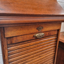 Antique Edwardian roll top Tambour file cabinet desk. This practical antique tambour front filing cabinet dates around 1900 in the Edwardian period and is constructed from Oak. This antique cabinet has an adjustable writing slope, above a tambour front with key and working lock. It has been sourced locally and is in good original detailed condition.