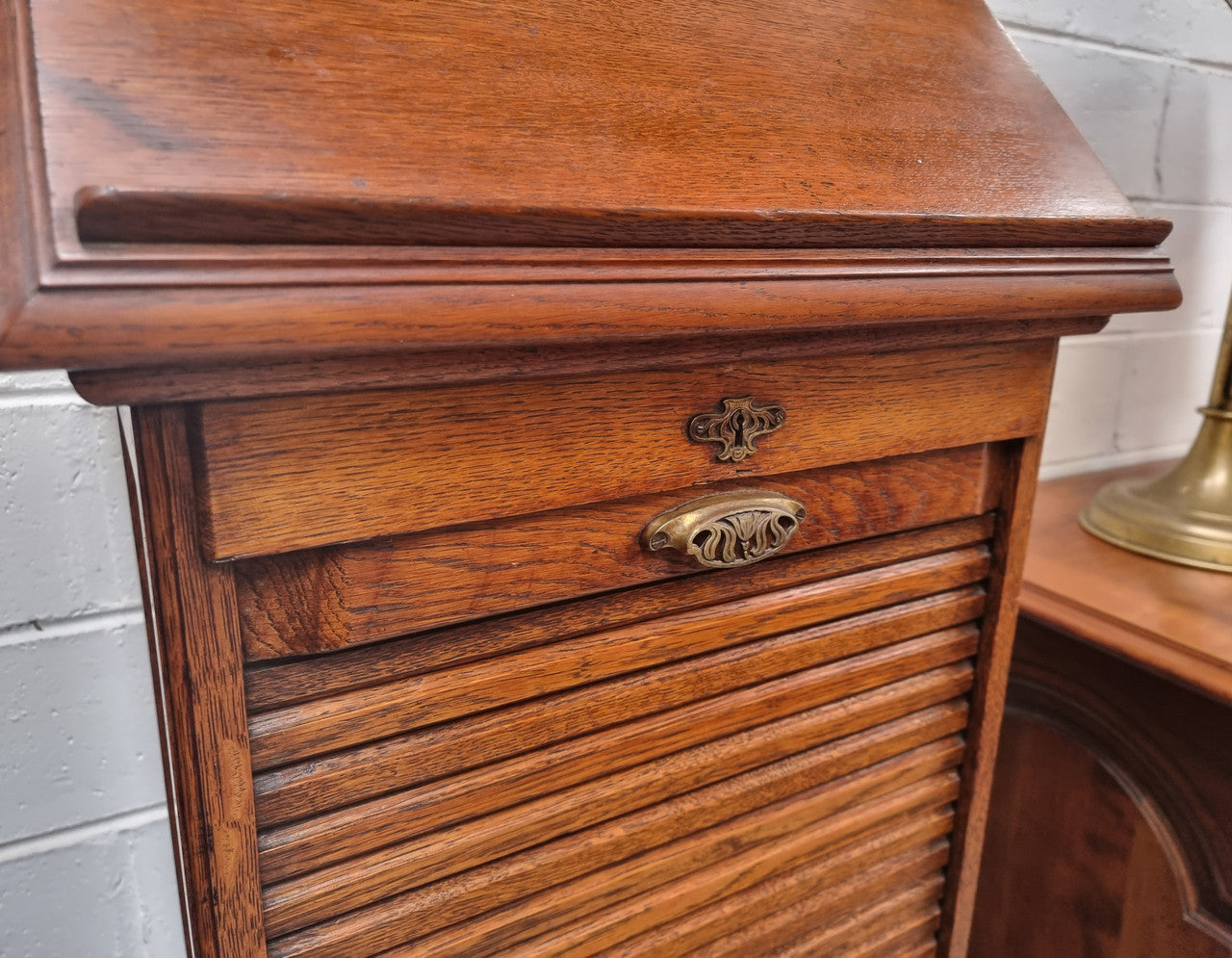 Antique Edwardian roll top Tambour file cabinet desk. This practical antique tambour front filing cabinet dates around 1900 in the Edwardian period and is constructed from Oak. This antique cabinet has an adjustable writing slope, above a tambour front with key and working lock. It has been sourced locally and is in good original detailed condition.