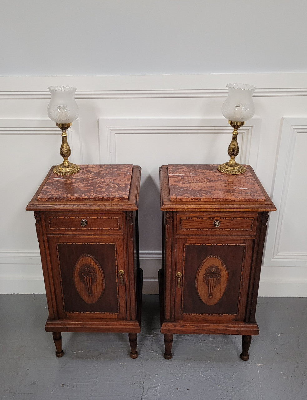 Pair of French Art Deco Oak and rouge inset marble top bedside cabinets. They have one drawer and one cupboard with elegant carving on the door. They have been sourced from France and are in good original detailed condition.