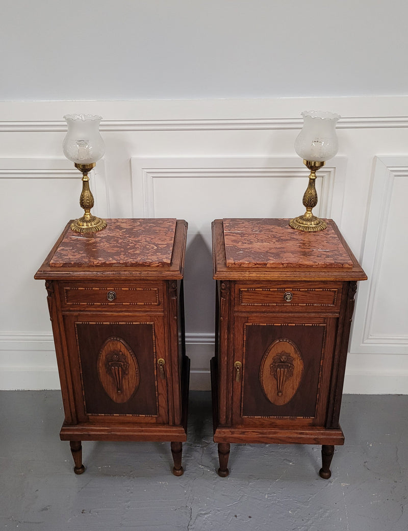 Pair of French Art Deco Oak and rouge inset marble top bedside cabinets. They have one drawer and one cupboard with elegant carving on the door. They have been sourced from France and are in good original detailed condition.