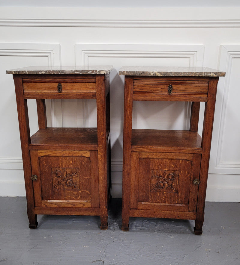 Pair of French Oak Arts & Crafts style marble top bedside cabinets. They have lovely carvings on the door, an open shelf in the middle and drawer at the top. They are in good original detailed condition.