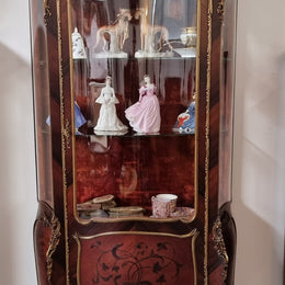 French Louis XV style marquetry inlaid vitrine with ormolu mounts and curved glass. The inside in lined with a red velvet upholstery and has two glass shelves. It has been sourced from France and is in good original detailed condition.