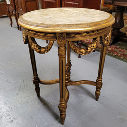 French Louis XVI style round marble topped gilded lamp/side table featuring lovely carved swags and undercarriage. It has been sourced from France and is in good original detailed condition.
