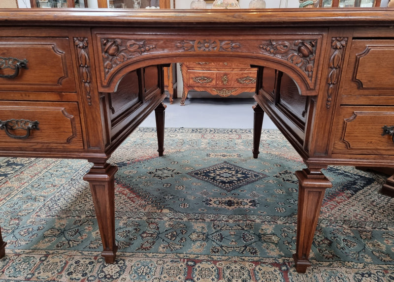 Substantial French Louis XVI style Oak partners desk. It has a beautiful leather top, two drawers on either side and decorative carvings throughout. Sourced from France and in good original detailed condition.