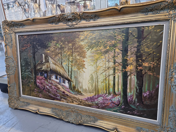 Vintage French oil painting on canvas in original gilt frame of "Forest Cottage Scene". Circa 1950's.