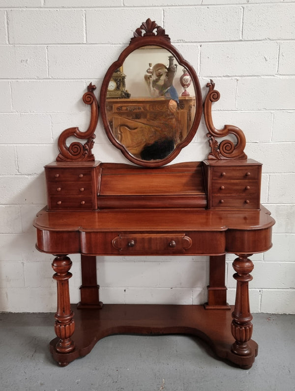 Victorian Mahogany duchess dressing table with tilt mirror on scrolled supports. It has seven trinket drawers and lift up storage. It is in good original condition and has been sourced locally.