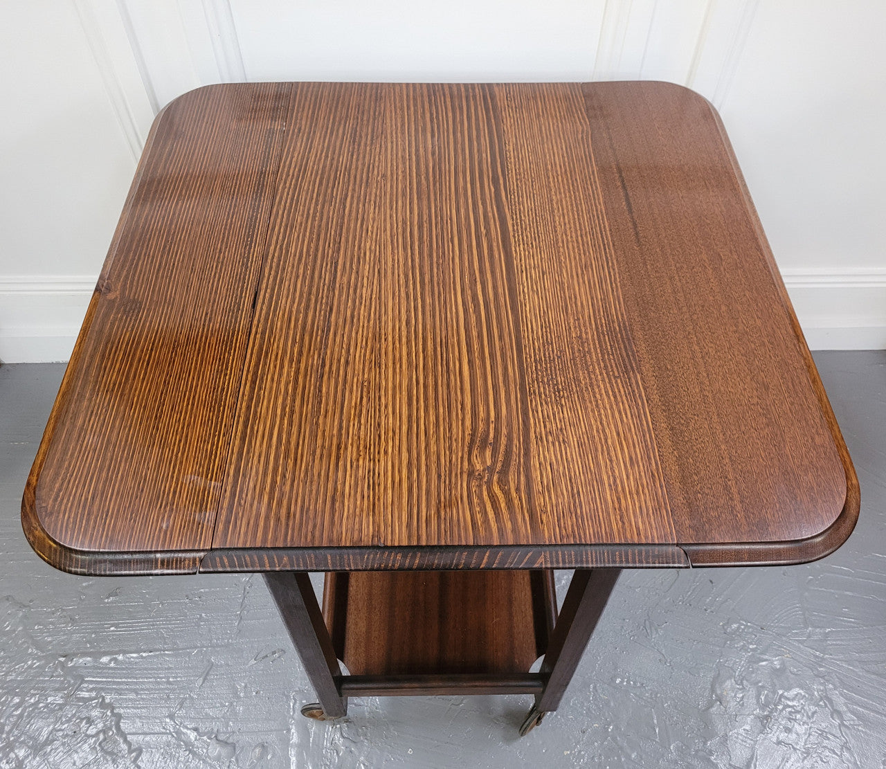 Oak drop leaf auto trolley on wheels. Both sides open up to make a larger table. It is in good original detailed condition.