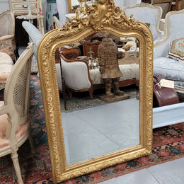 Beautiful French Napoleon III Louis XV style gilt framed bevelled mirror with an ornate crest on top. It has been sourced from France and is in good original detailed condition with the mirror showing signs of age.