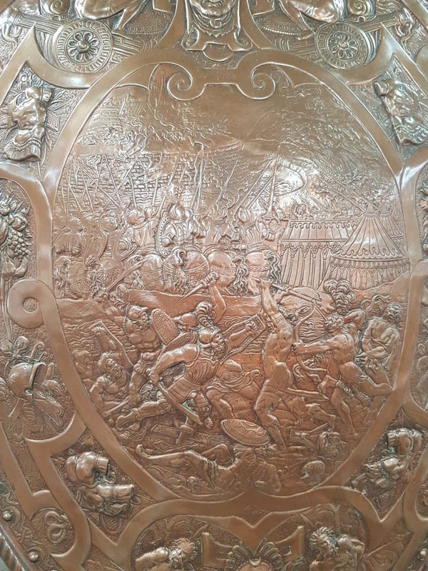 A beautiful European antique repousse copper shield, depicting a battle scene and with metal swords. It has been sourced from France and is in good original condition.