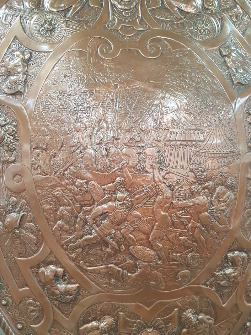 A beautiful European antique repousse copper shield, depicting a battle scene and with metal swords. It has been sourced from France and is in good original condition.