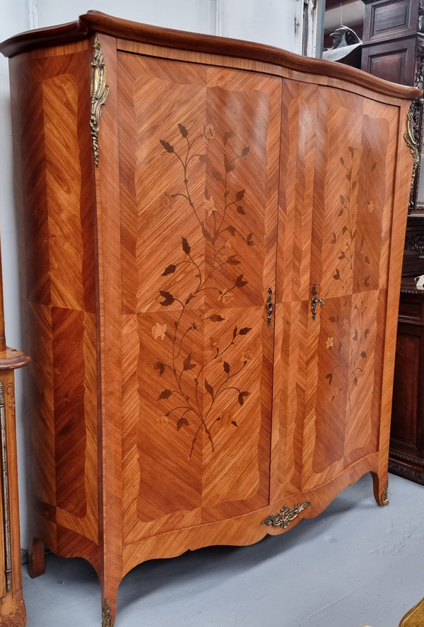 Charming French Louis XV Style Marquetry Inlaid Two Door Armoire. Features three adjustable shelves and ormolu trim. It has been sourced from France and is in good original condition.