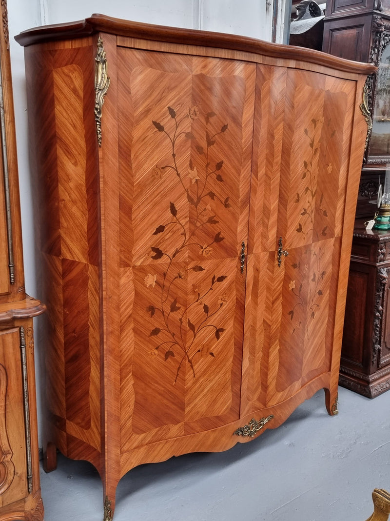 Charming French Louis XV Style Marquetry Inlaid Two Door Armoire. Features three adjustable shelves and ormolu trim. It has been sourced from France and is in good original condition.