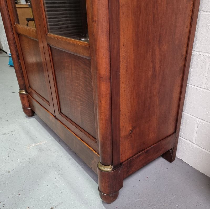 Grand French Mahogany Empire two door bookcase. It has beautiful glass doors and has three fully adjustable shelves. It has been sourced from France and is in good original detailed condition.