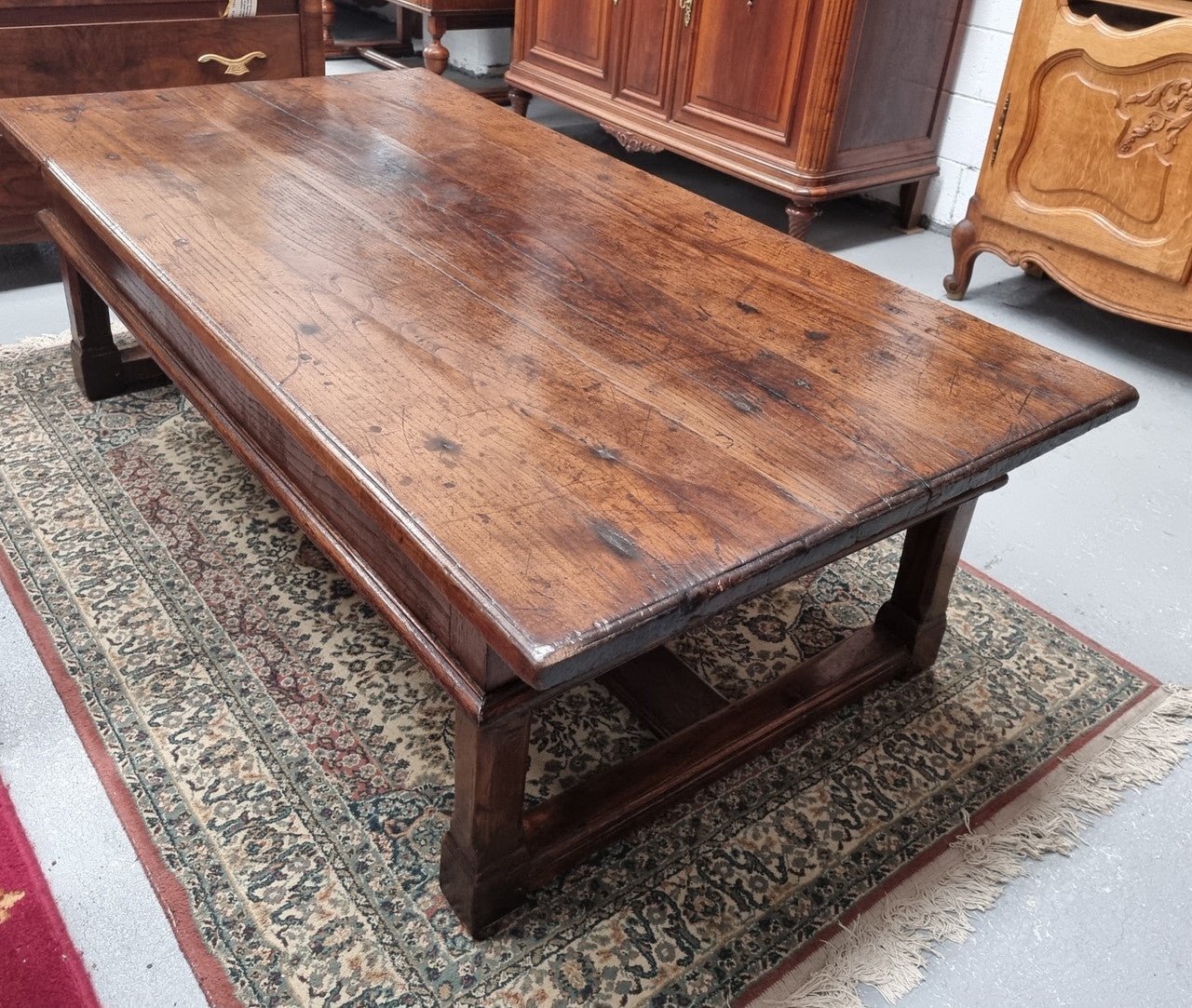Impressive large size rustic French Oak coffee table with two drawers on a stretcher base. In good original detailed condition and sourced from France.