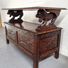 Unusual English Oak Monks Bench.  The tabletop is set onto a lift top chest in such a way that when the table is not in use, the top pivots to a vertical position and becomes the back of a Settle. Carved Lion table rests and carving to front.  In good, detailed condition.