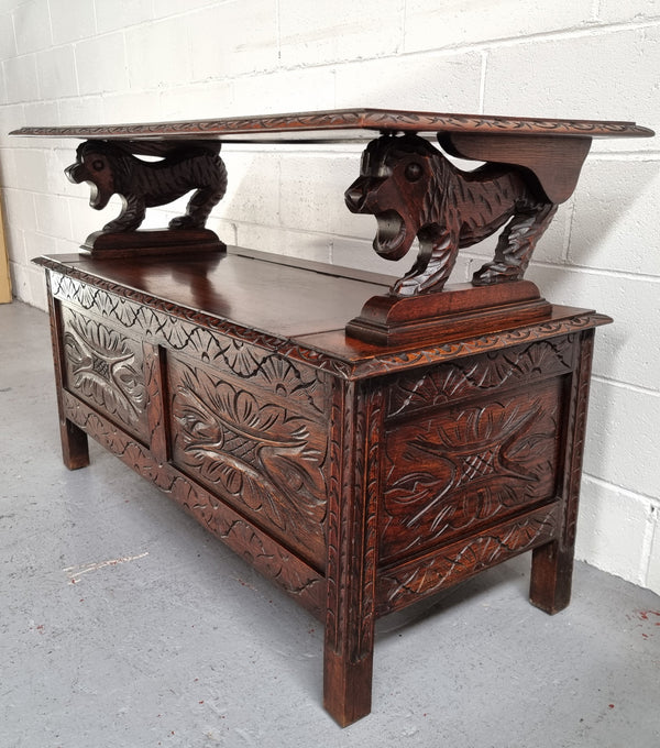 Unusual English Oak Monks Bench.  The tabletop is set onto a lift top chest in such a way that when the table is not in use, the top pivots to a vertical position and becomes the back of a Settle. Carved Lion table rests and carving to front.  In good, detailed condition.