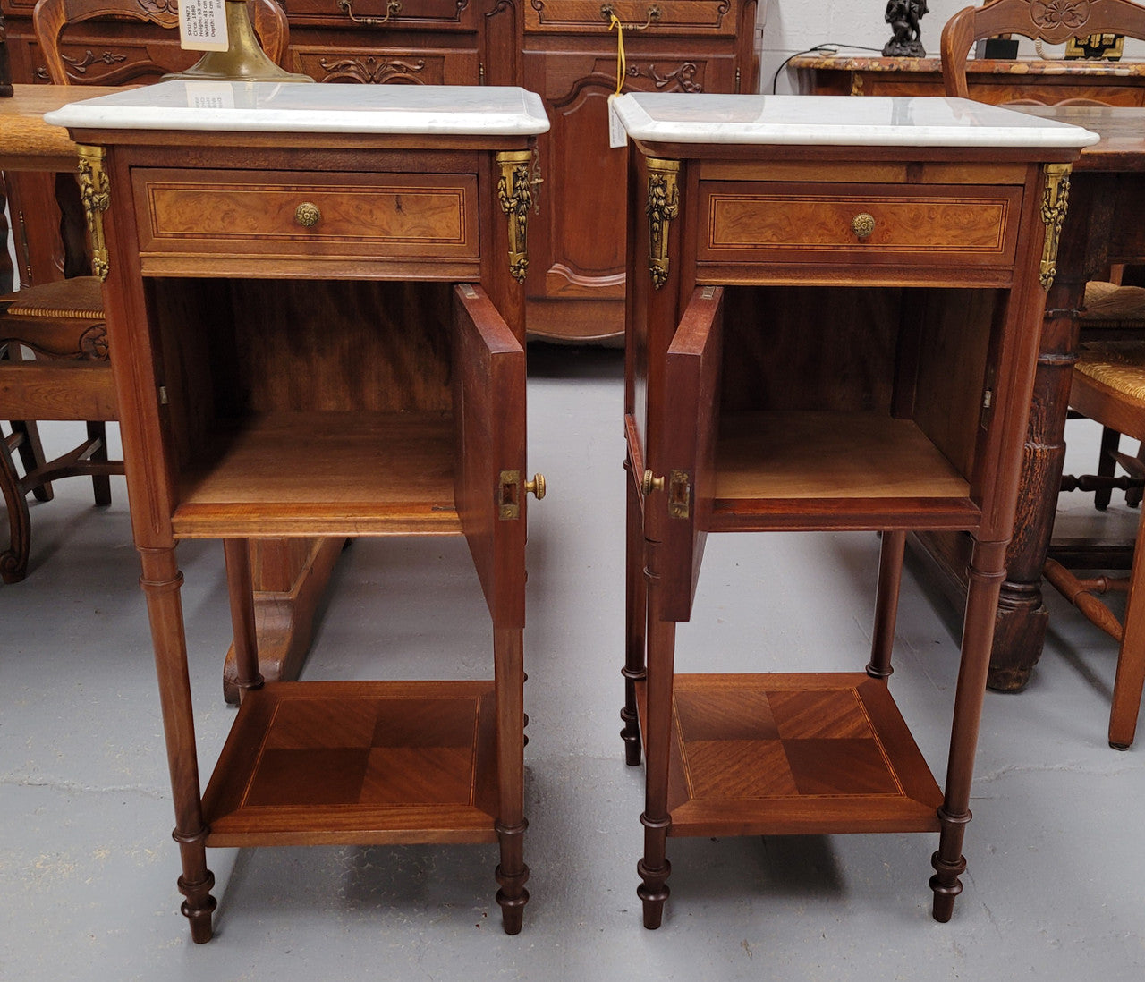 Pair of white marble topped Louis 16th style bedside cabinets consisting of one drawer and one cupboard.  Inlaid with burr walnut and has decorative mounts. They have been sourced from France and are in good original condition.