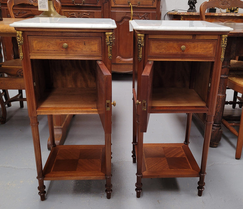 Pair of white marble topped Louis 16th style bedside cabinets consisting of one drawer and one cupboard.  Inlaid with burr walnut and has decorative mounts. They have been sourced from France and are in good original condition.