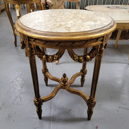 French Louis XVI style round marble topped gilded lamp/side table featuring lovely carved swags and undercarriage. It has been sourced from France and is in good original detailed condition.