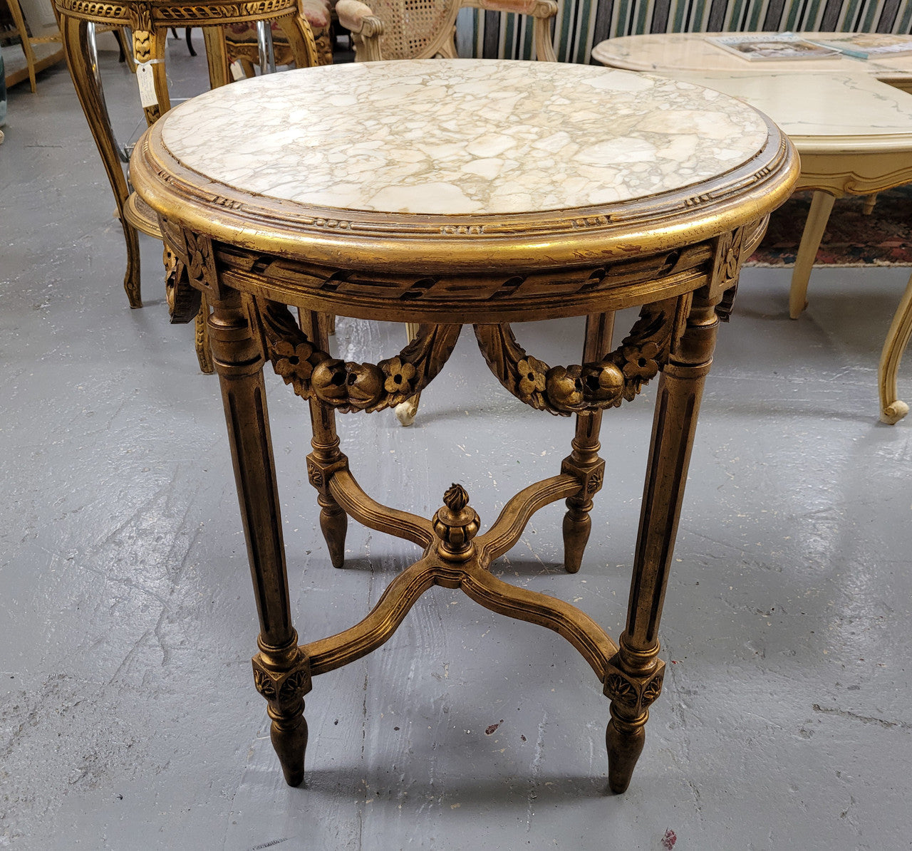 French Louis XVI style round marble topped gilded lamp/side table featuring lovely carved swags and undercarriage. It has been sourced from France and is in good original detailed condition.