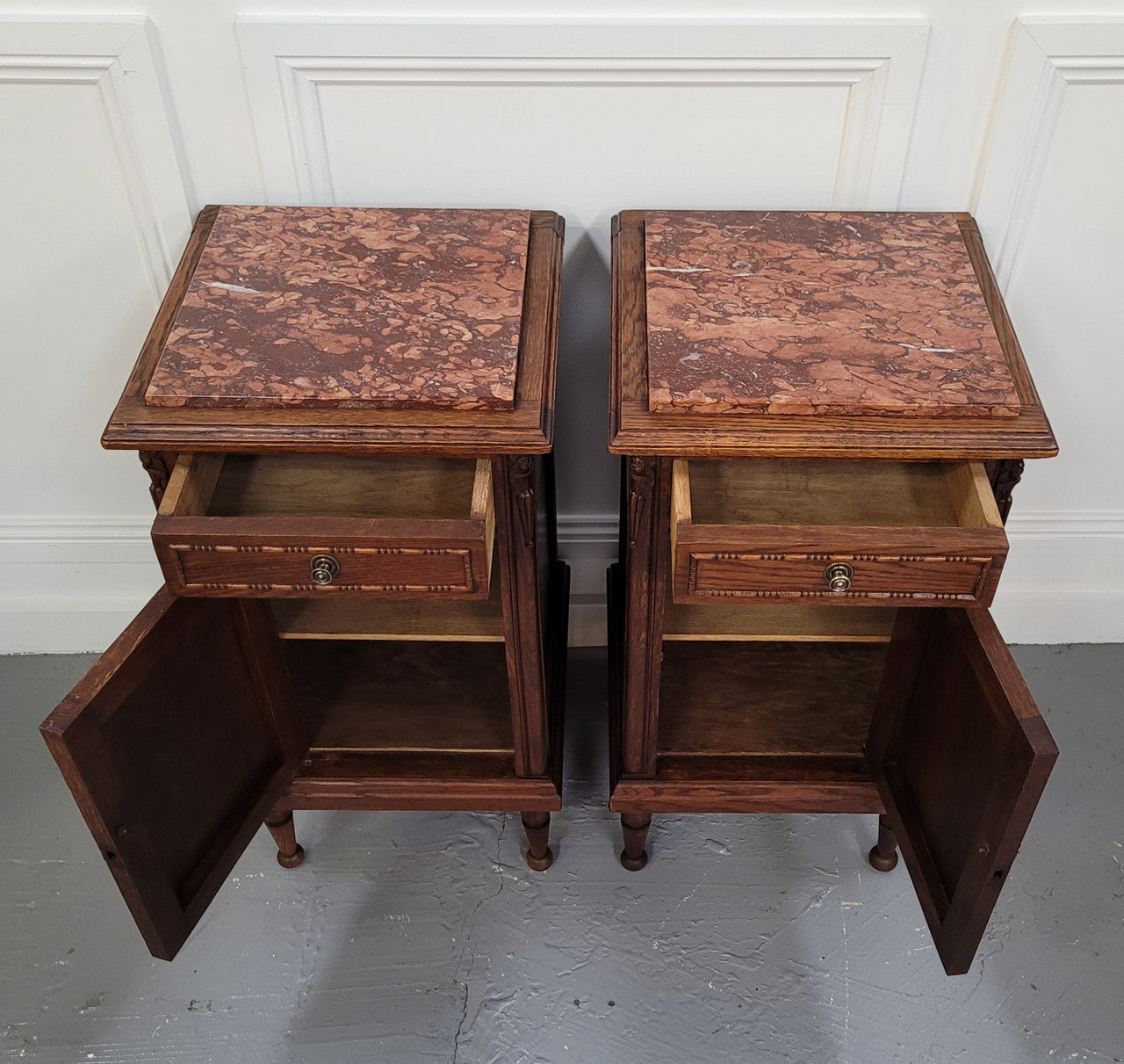 Pair of French Art Deco Oak and rouge inset marble top bedside cabinets. They have one drawer and one cupboard with elegant carving on the door. They have been sourced from France and are in good original detailed condition.
