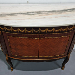 Vintage French style marble top two door half-moon buffet with beautiful decorative brass gilt mounts. In good original detailed condition.