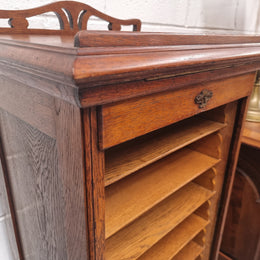 Antique Edwardian roll top Tambour file cabinet desk. This practical antique tambour front filing cabinet dates around 1900 in the Edwardian period and is constructed from Oak. This antique cabinet has an adjustable writing slope, above a tambour front with key and working lock. It has been sourced locally and is in good original detailed condition.