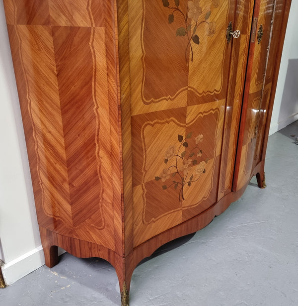 Tall French Marquetry inlaid armoire / bookcase with ormolu mounts. The interior has six fully adjustable shelves and two drawers. It is in good original detailed condition.