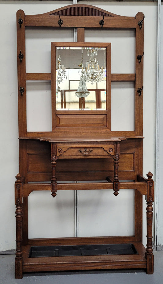 Impressive Oak hall stand of grand portions. Plenty of storage with a drawer, plenty of hooks and two sections for umbrealls/ walking sticks. It is in good original detailed condition.