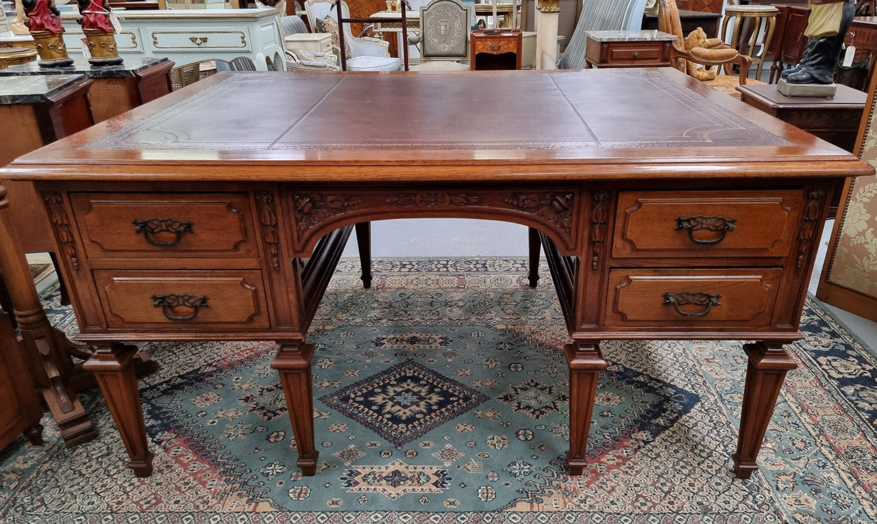 Substantial French Louis XVI style Oak partners desk. It has a beautiful leather top, two drawers on either side and decorative carvings throughout. Sourced from France and in good original detailed condition.