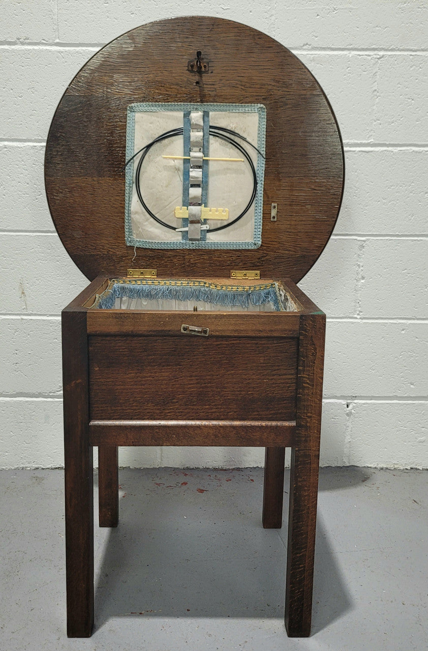 Fabulous round oak side table which also has a hidden sewing box underneath with lovely original blue satin lining and Includes pictured sewing items. It is in good original condition.