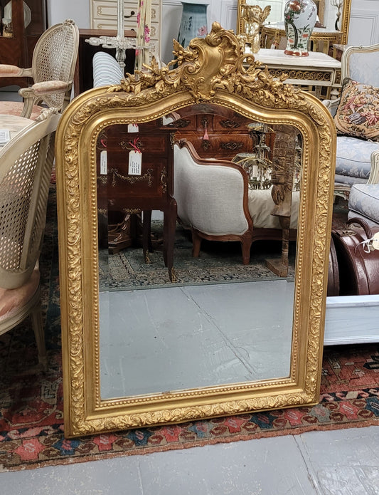 Beautiful French Napoleon III Louis XV style gilt framed bevelled mirror with an ornate crest on top. It has been sourced from France and is in good original detailed condition with the mirror showing signs of age.