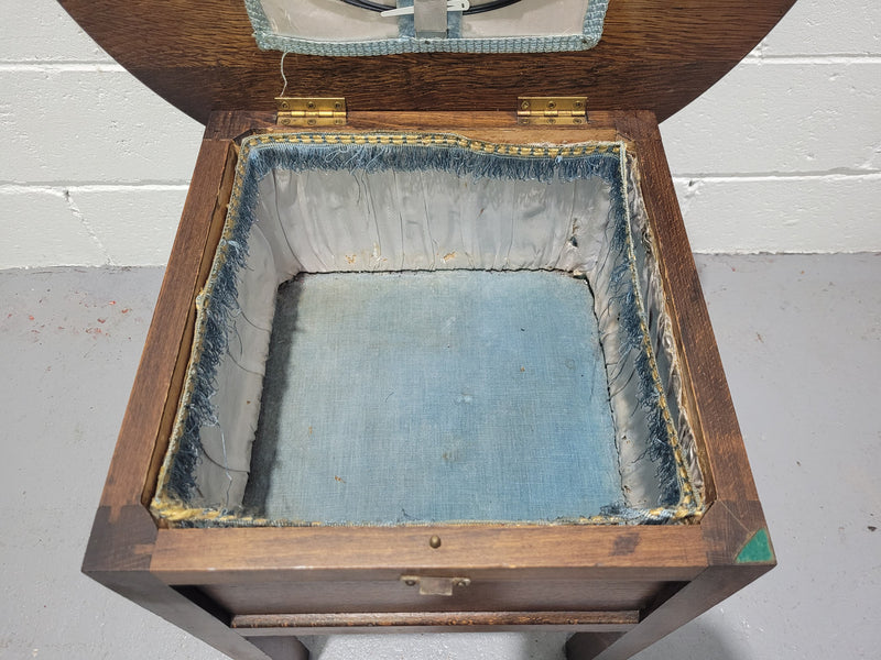 Fabulous round oak side table which also has a hidden sewing box underneath with lovely original blue satin lining and Includes pictured sewing items. It is in good original condition.