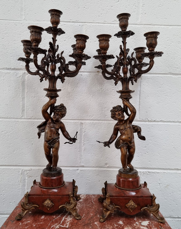 Pair of highly decorative French cherub candelabras with bronzed metal and marble. In good original detailed condition.