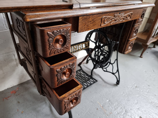 Singer Treadle sewing machine with six decorative side drawers and one centre drawer in Oak on cast iron base. It is in original condition.