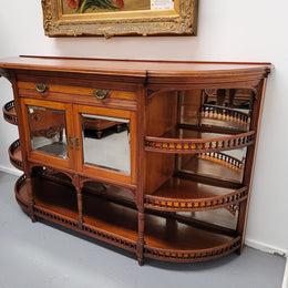 A high quality Antique Walnut sideboard featuring two mirrored doors, two drawers and five open shelf areas with mirror backing. It is in good original detailed condition.