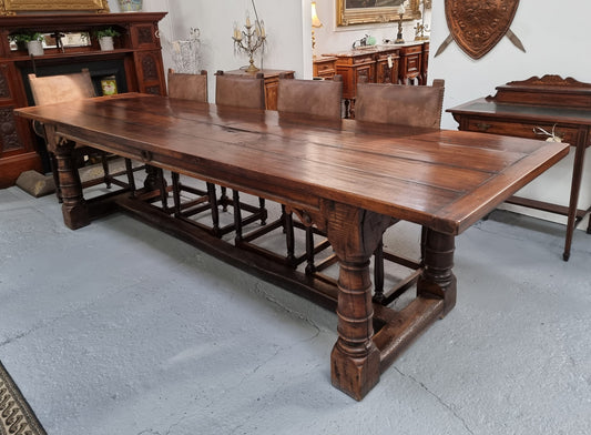 Amazing three meter long dark Oak Farmhouse dining table with a pedestal base. Comes with matched set of 10 very comfortable leathered chairs. All is in very good original detailed condition.