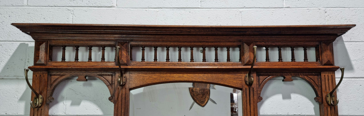 Grand Henry 2nd Style French Oak hall stand with 12 hanging hooks. Also has one cupboard and drawer for storage along with a mirror and two areas either side for umbrellas and walking sticks. In good original detailed condition.