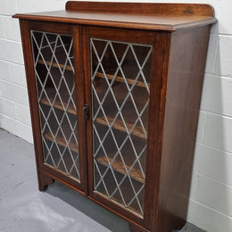 Lovely leadlight two door Oak bookcase/display cabinet with four wooden shelves. It is in good original detailed condition.