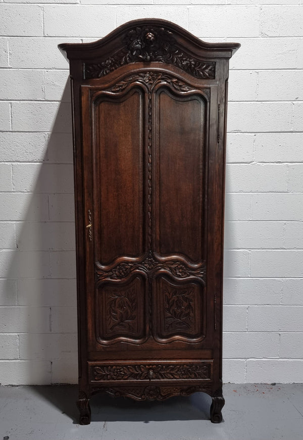 An Attractive French Louis XV style single-door ‘Marriage Armoire’. Beautifully arched crest with detailed carved flowers along with an arched single door which repeats the floral carvings. It is also has plenty of storage space with three adjustable shelves along with a drawer at the bottom. All in good original detailed condition.