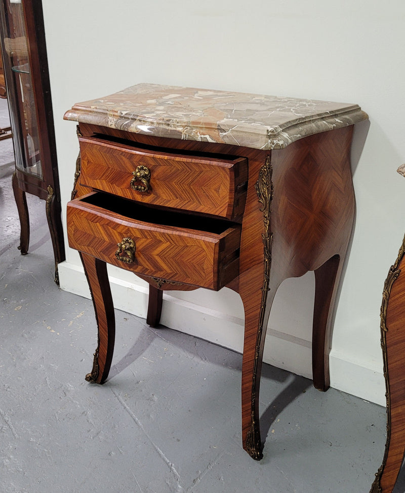 Pair of Louis XV commode style two drawer bedsides with beautiful marble tops and decorative mounts. They are a rare size and are in good, detailed condition.