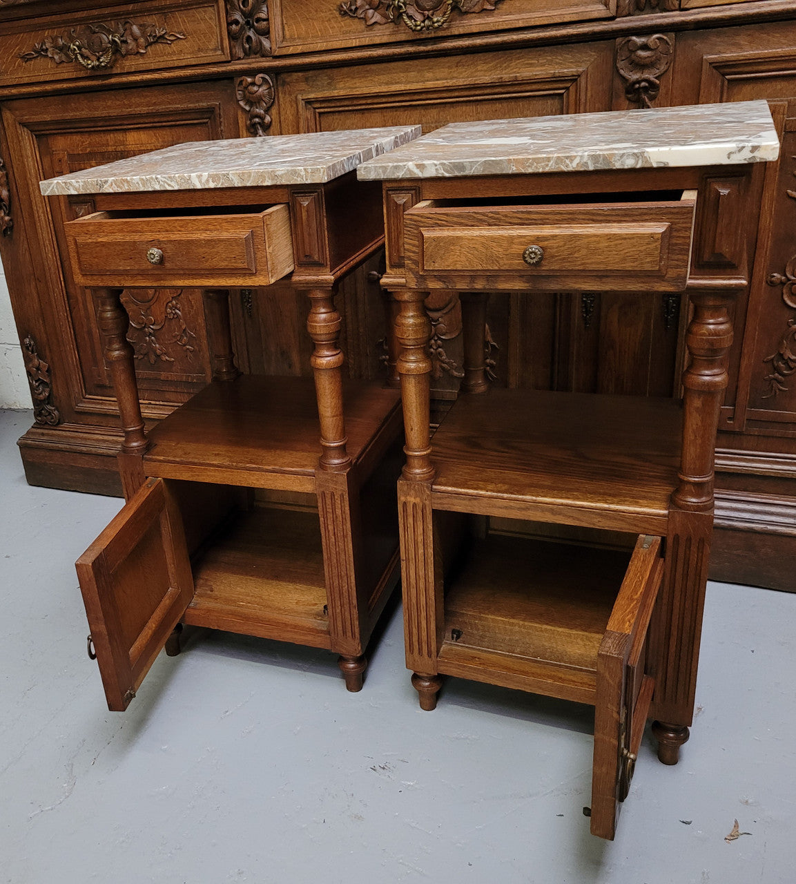 Pair of French Antique Oak marble top bedsides Henry II style. They have a drawer, cupboard and an open shelf for all your storage needs. They have been sourced from France and are in good original detailed condition.